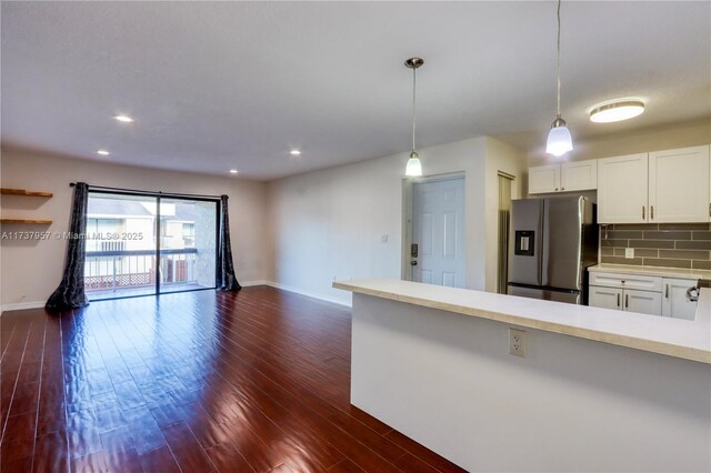 kitchen with hanging light fixtures, white cabinetry, dark wood-type flooring, and stainless steel fridge