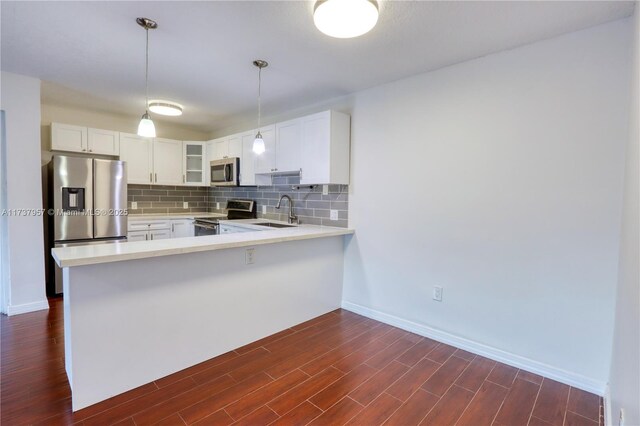 kitchen with dark wood-type flooring, white cabinetry, pendant lighting, stainless steel appliances, and backsplash