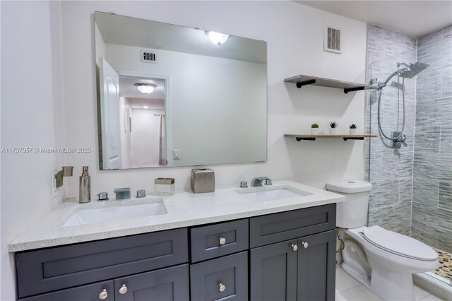 bathroom with tiled shower, vanity, and toilet