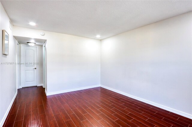 empty room with dark hardwood / wood-style floors and a textured ceiling