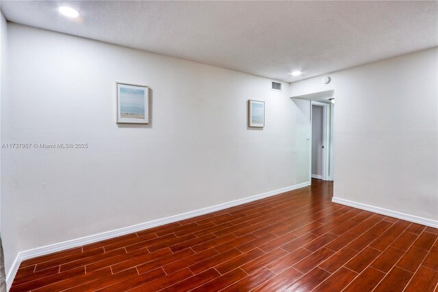 unfurnished room with a textured ceiling and dark hardwood / wood-style flooring