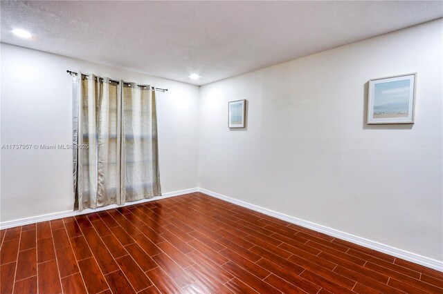 spare room featuring dark hardwood / wood-style floors and a textured ceiling