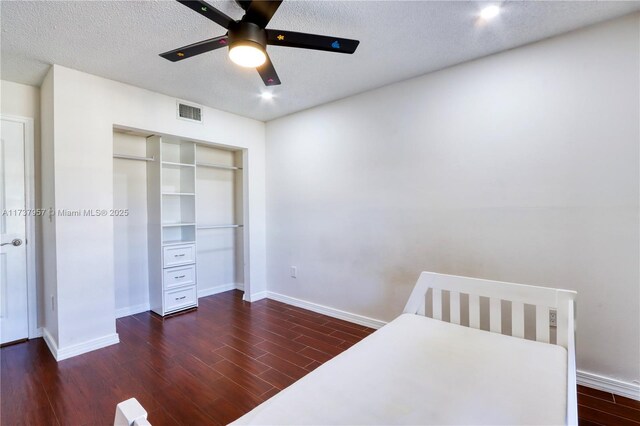 bedroom with dark wood-type flooring, ceiling fan, a closet, and a textured ceiling