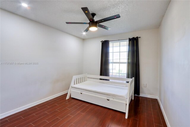 bedroom with dark wood-type flooring, ceiling fan, and a textured ceiling