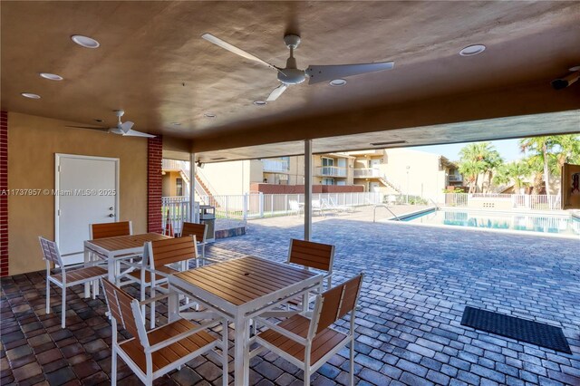 view of patio with a community pool and ceiling fan