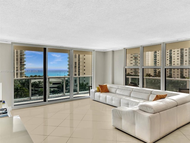 tiled living room featuring floor to ceiling windows, a textured ceiling, and a water view