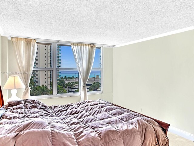 bedroom featuring ornamental molding, a water view, and a textured ceiling