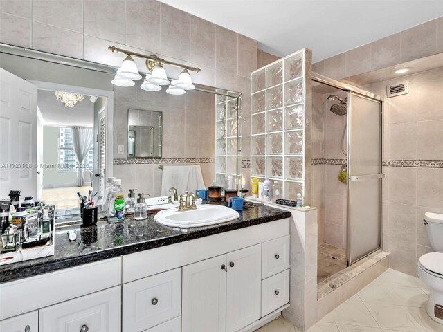 bathroom featuring vanity, toilet, an enclosed shower, and tile walls