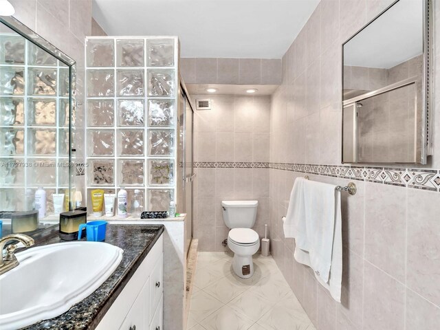 bathroom with tile walls, vanity, tile patterned flooring, and a shower with shower door