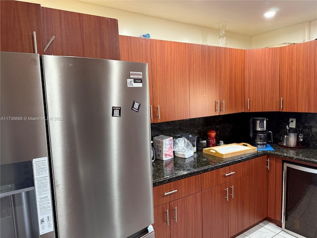 kitchen featuring light tile patterned floors, stainless steel refrigerator, dark stone countertops, backsplash, and beverage cooler