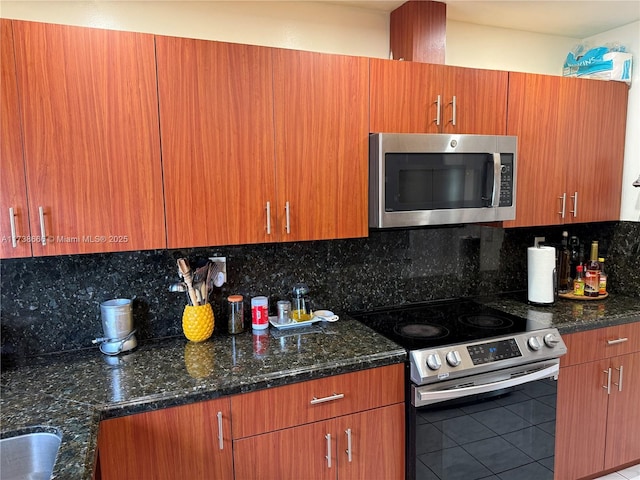 kitchen featuring backsplash, stainless steel appliances, and dark stone counters