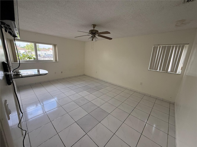 empty room featuring ceiling fan, a textured ceiling, and light tile patterned floors