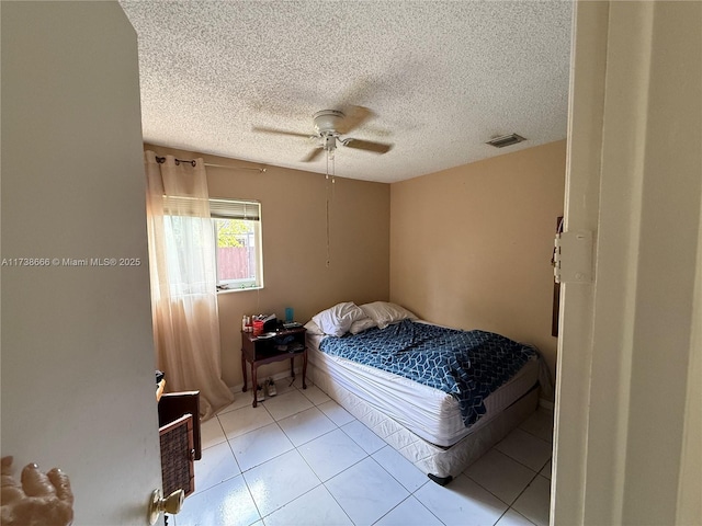 tiled bedroom with ceiling fan and a textured ceiling