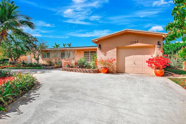 single story home featuring an attached garage, driveway, stone siding, and stucco siding