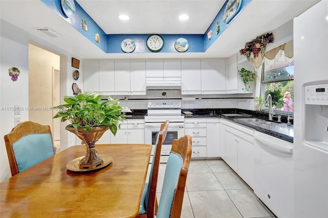kitchen featuring dark countertops, white appliances, white cabinetry, under cabinet range hood, and visible vents