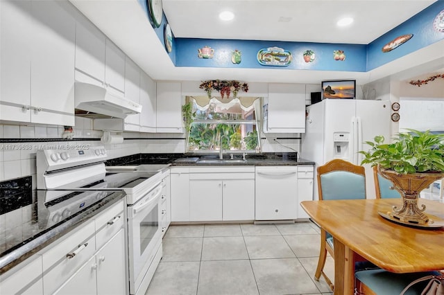 kitchen with white cabinets, under cabinet range hood, a sink, and white appliances