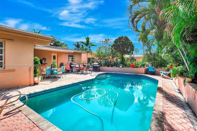 view of swimming pool featuring grilling area, a fenced in pool, and a patio area
