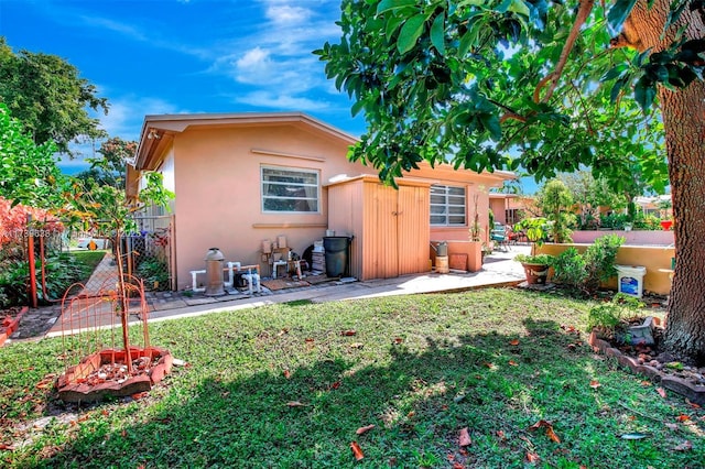 back of property featuring stucco siding, fence, a patio area, and a yard