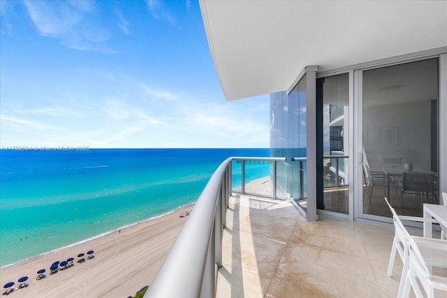 balcony featuring a view of the beach and a water view