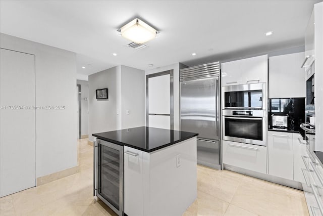 kitchen with appliances with stainless steel finishes, a center island, wine cooler, white cabinets, and light tile patterned flooring