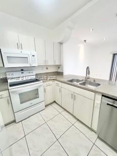 kitchen featuring light tile patterned flooring, white appliances, sink, and white cabinets