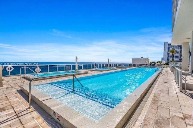 view of swimming pool featuring a patio area and a water view