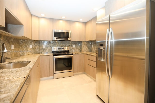 kitchen with sink, light stone counters, light brown cabinets, stainless steel appliances, and decorative backsplash