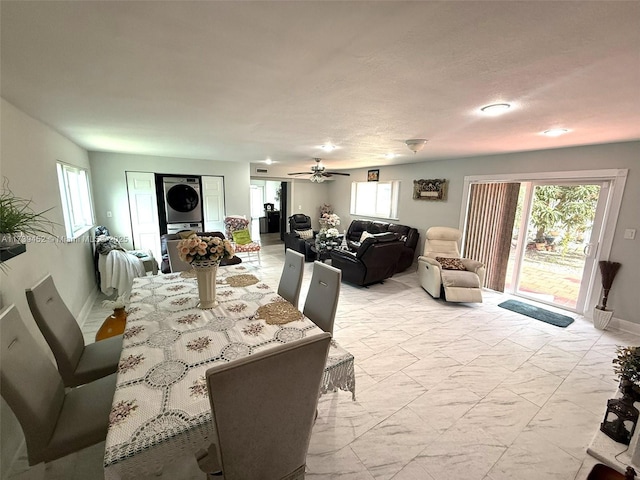 dining area with ceiling fan, a healthy amount of sunlight, and stacked washer / drying machine