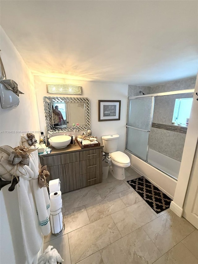 full bathroom with toilet, vanity, and shower / bath combination with glass door