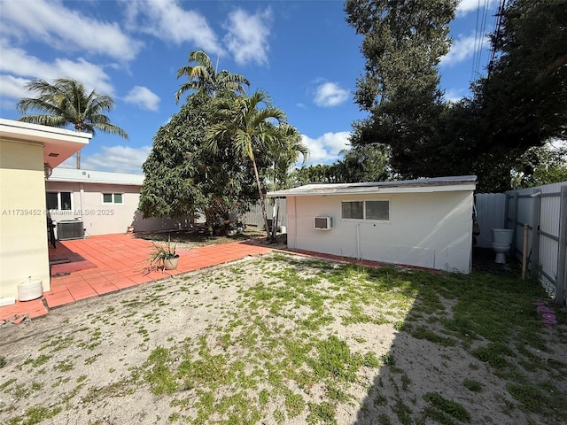 view of yard featuring an AC wall unit, central AC unit, and a patio area