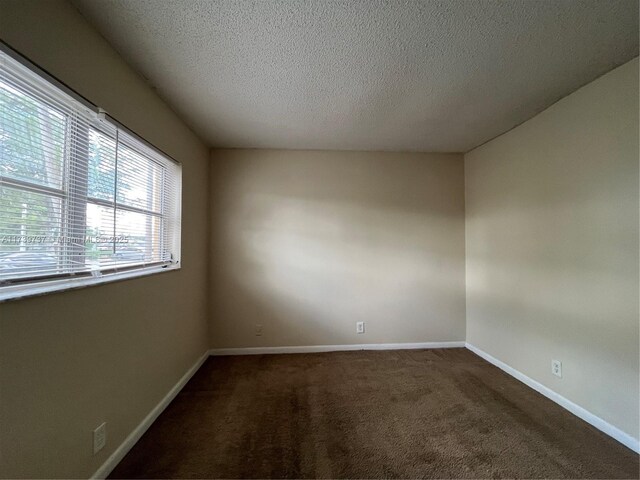 carpeted empty room with a textured ceiling