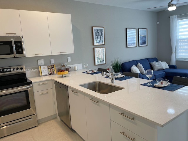 kitchen with white cabinetry, appliances with stainless steel finishes, sink, and kitchen peninsula