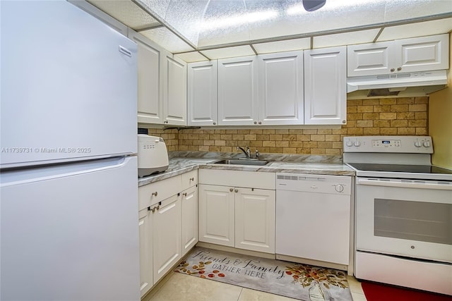 kitchen featuring sink, white appliances, light tile patterned floors, white cabinetry, and decorative backsplash