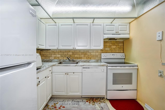 kitchen with sink, white cabinets, white appliances, light stone countertops, and backsplash