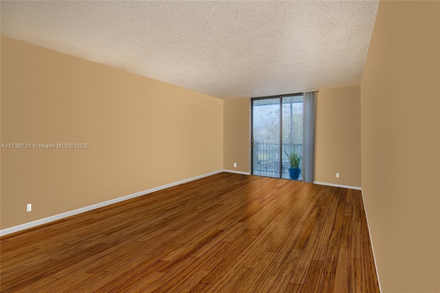 spare room with hardwood / wood-style floors, a wall of windows, and a textured ceiling