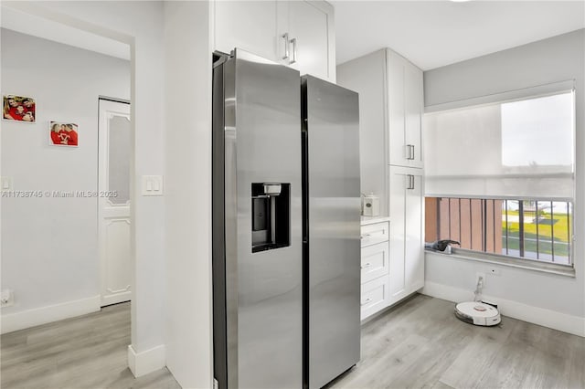 kitchen featuring stainless steel refrigerator with ice dispenser, light hardwood / wood-style floors, and white cabinets