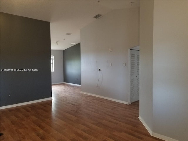 empty room with lofted ceiling and dark wood-type flooring