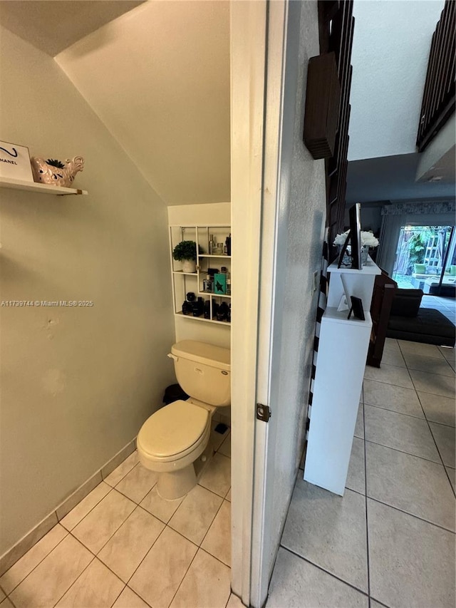 bathroom featuring tile patterned flooring, vaulted ceiling, and toilet