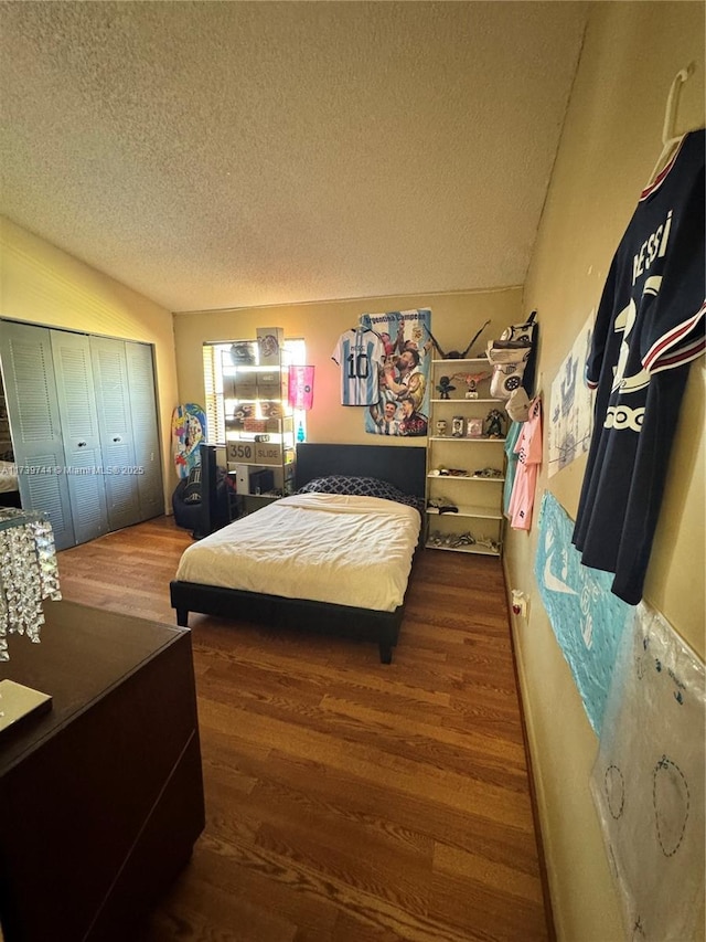 bedroom with dark wood-type flooring, a closet, a textured ceiling, and vaulted ceiling