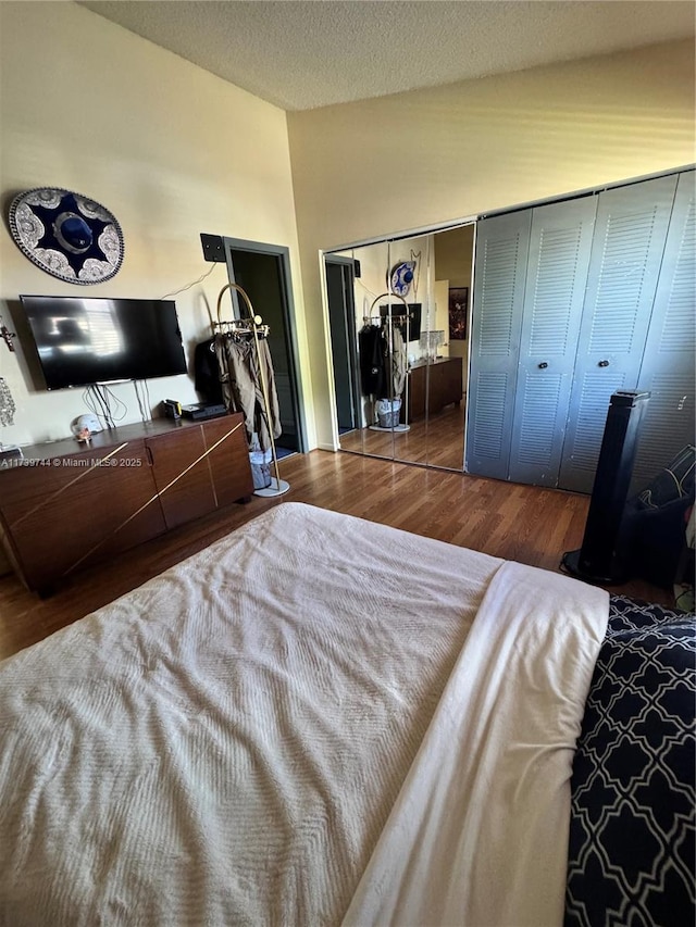 bedroom with dark hardwood / wood-style flooring, vaulted ceiling, and a textured ceiling