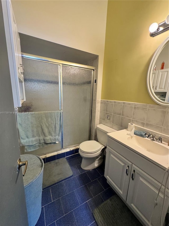 bathroom with tile walls, vanity, an enclosed shower, toilet, and tile patterned floors