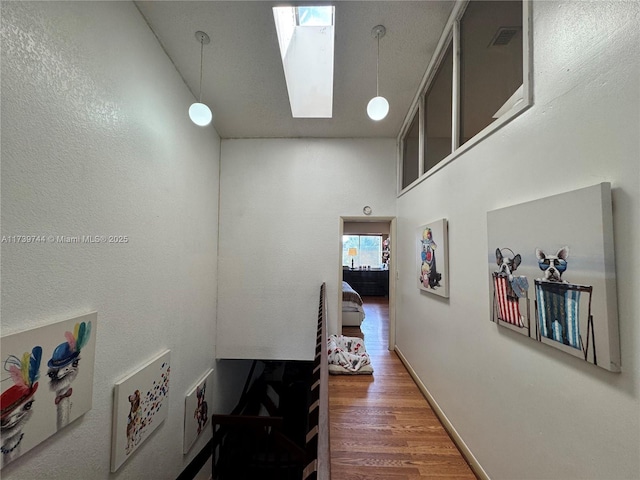 corridor featuring hardwood / wood-style floors and a skylight