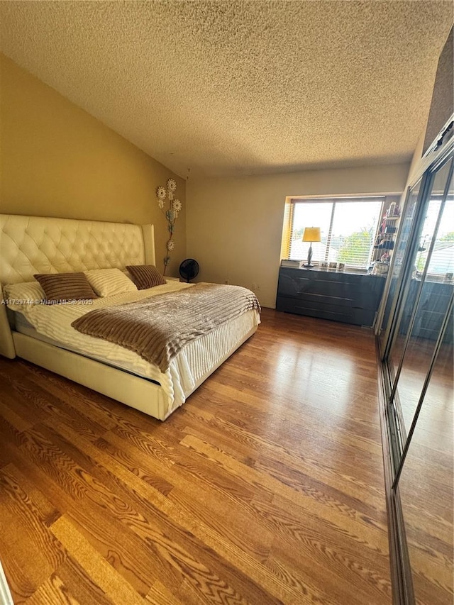 bedroom with wood-type flooring, access to exterior, and a textured ceiling