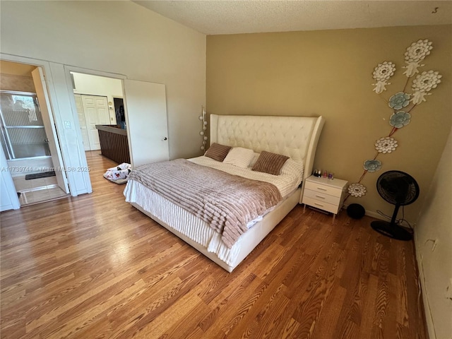 bedroom featuring hardwood / wood-style flooring, lofted ceiling, and a textured ceiling