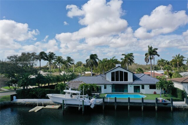 back of property with a water view and a lawn