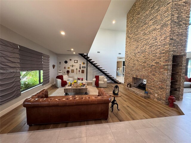 living room with hardwood / wood-style flooring, a towering ceiling, and a fireplace