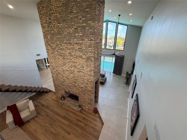 unfurnished living room with light tile patterned floors, brick wall, and a high ceiling