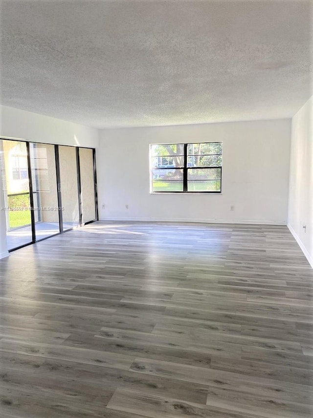 empty room with dark hardwood / wood-style flooring and a textured ceiling