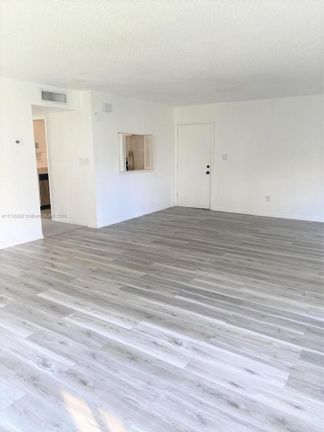 unfurnished room featuring hardwood / wood-style flooring and a textured ceiling