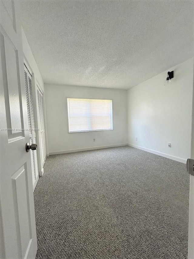 carpeted spare room with a textured ceiling